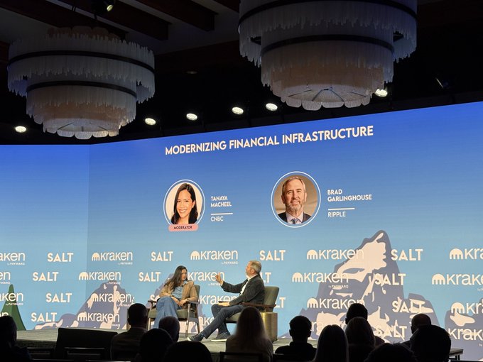 A panel discussion titled 'MODERNIZING FINANCIAL INFRASTRUCTURE' at a SALT/Kraken event featuring moderator Tamara Macheel (CNBC) and speaker Brad Garlinghouse (Ripple).