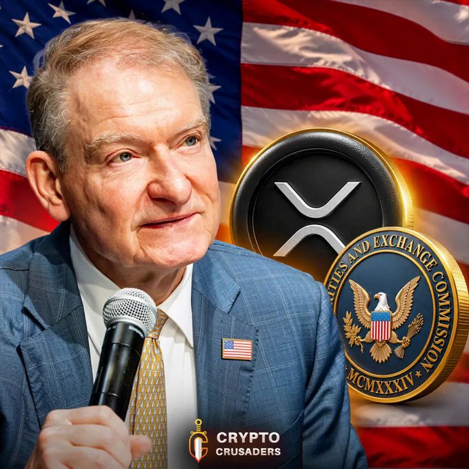 Promotional image featuring an older man in a blue suit with a US flag pin speaking into a microphone, set against an American flag backdrop alongside XRP and SEC logos, branded 'Crypto Crusaders'.