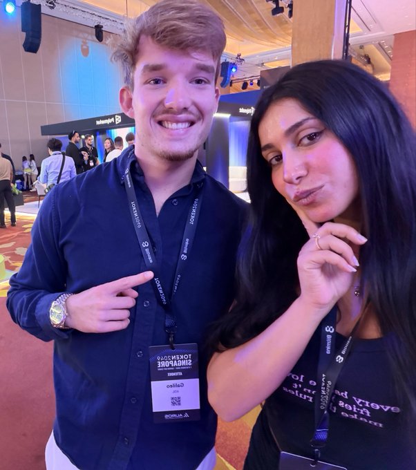 Two attendees pose together at the Token2049 Singapore conference, with the woman's badge upside-down displaying "Galinea / Crypto Gal" and the man's lanyard identifying him as "galileo," matching the post's shoutout to @galileowilson, captioned as one of the "ct legends" met at the event.