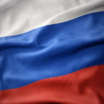 Close-up of a waving flag with horizontal white, blue, and red stripes, resembling the Russian flag.