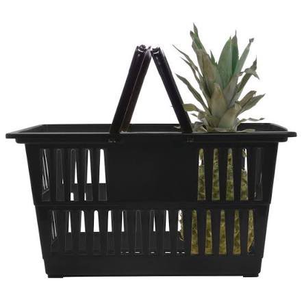 A black plastic shopping basket containing a pineapple, viewed against a white background.