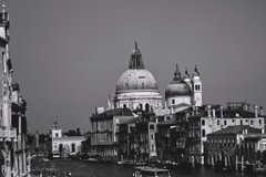 A black and white photograph captures the skyline of Venice, prominently featuring the domed Basilica di Santa Maria della Salute.