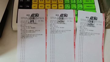 Three Chinese lottery tickets (体彩) placed on a desk next to a colorful children's educational keyboard with labeled function keys.