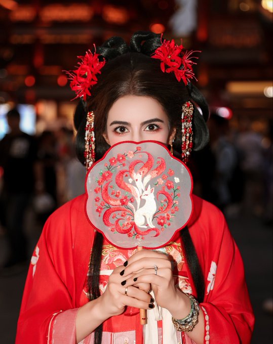 A woman in traditional red Chinese attire with elaborate floral hair ornaments holds a decorative fan depicting a white rabbit and red phoenix design in front of her lower face, fitting the post's announcement of joining the "Bored Ape Yacht Club • Shanghai."