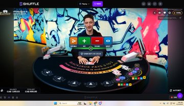 A screenshot of an online live blackjack game called 'Shuffle' featuring a male dealer at a virtual table with betting controls (2x, +, -, ||) displayed on the screen.