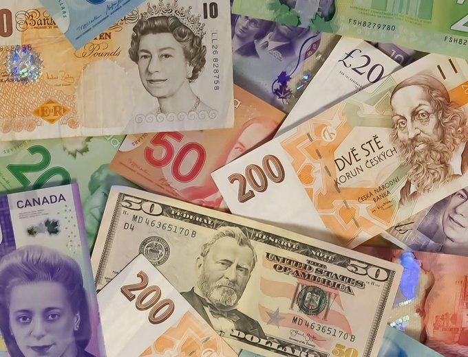 A collage of various international banknotes including British pounds, Canadian dollars, Czech koruna, and US dollars.