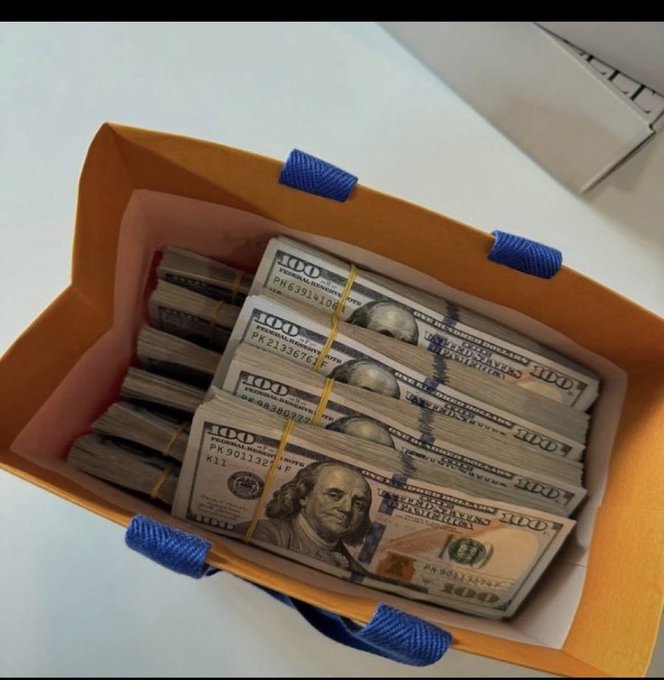 Stacks of $100 US bills, banded together, fill an orange shopping bag with blue handles, reflecting the optimistic spirit of the post's "Gm people may today good to us" greeting.