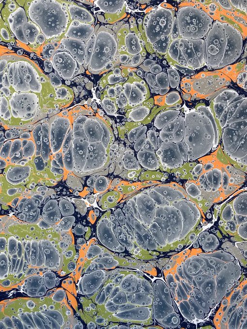 An abstract marbled pattern in shades of gray, white, green, and orange with circular cell-like formations and dark veining.