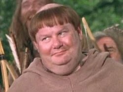 A still of a young man with light brown hair wearing a brown hooded sweatshirt, appearing to be a character from a medieval-themed production.