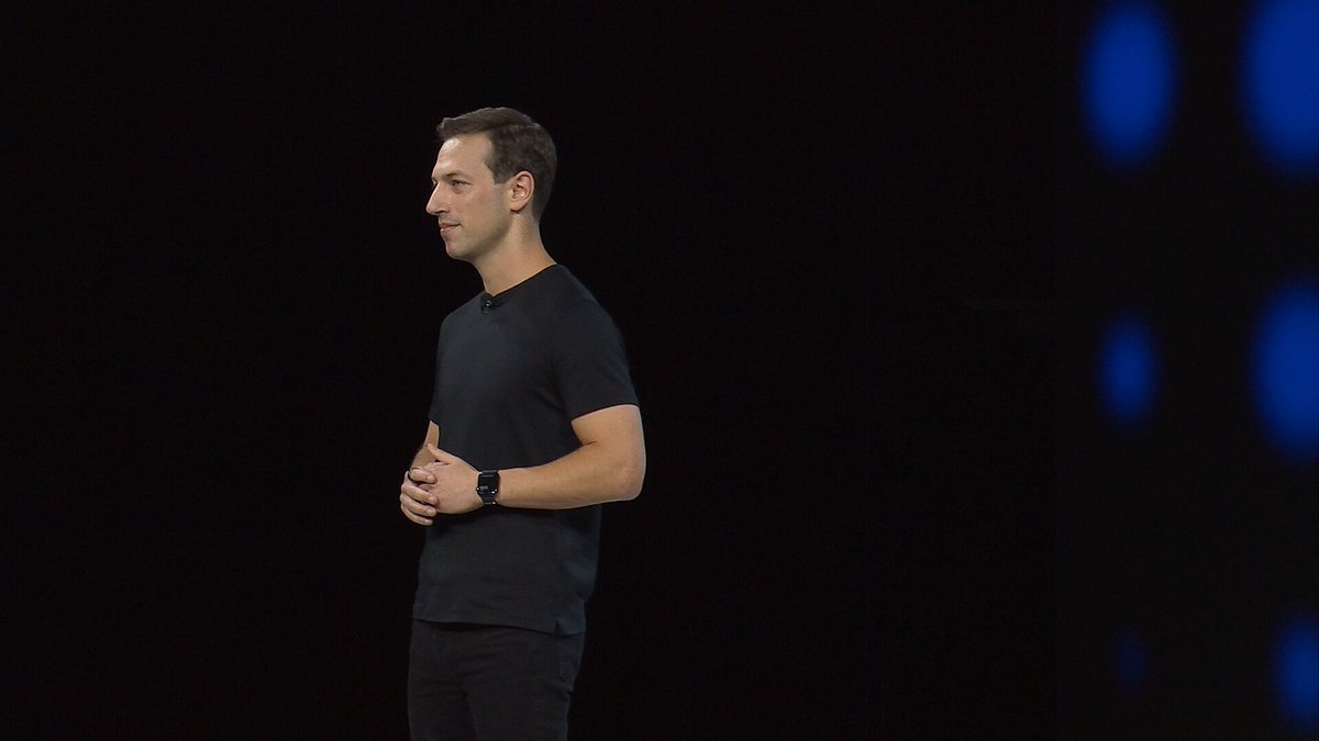 The image features a man standing against a black background, wearing a black shirt and pants. He has his hands together as if giving a speech or presentation. The caption of the image reads "Not the first hehe1hhe..... all volume is in Backpack Solana real stock!". This suggests that the image might be related to an event where the man is speaking, such as a conference or seminar.

The background consists of blue dots and a black wall, which contrasts with the man's attire and adds depth to the image. The overall composition creates a sense of focus on the speaker while also highlighting his presence against the contrasting backdrop.