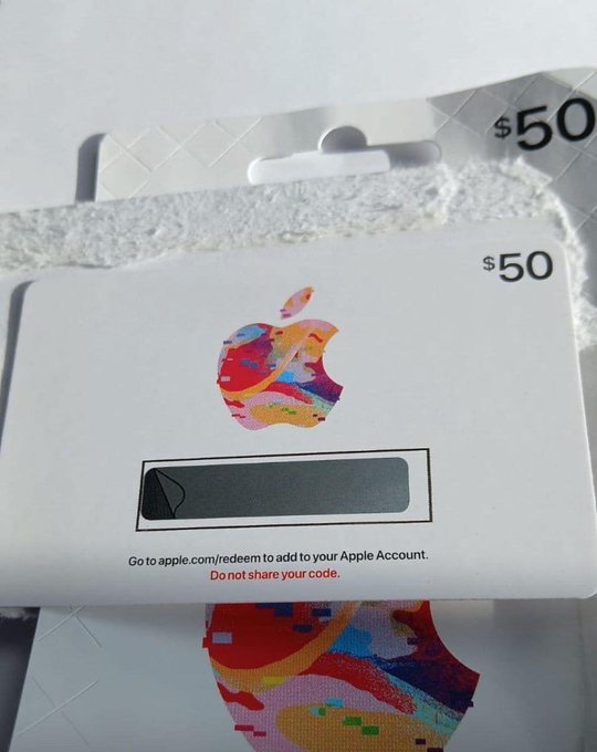 Two Apple gift cards worth $50 each, with one card's redemption code partially scratched off, featuring instructions to go to apple.com/redeem.