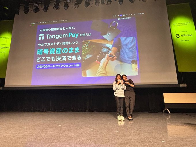 Two presenters stand on stage at "BitSummit Drift" showcasing the Tangem Pay hardware wallet, with a large screen behind them displaying a promotional slide in Japanese highlighting Tangem's pastel-colored card-shaped design and the tagline "次世代のハードウェアウォレット" (next-generation hardware wallet). The image reflects the post's appreciation for the sponsorship opportunity and Tangem's distinctive cute, colorful aesthetic that appeals to a broad audience.