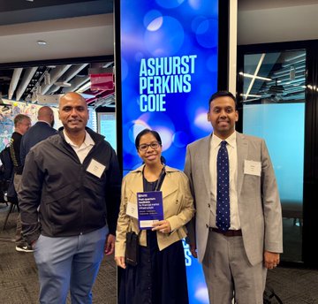 Akshay Thakur and a colleague from BitGo pose beside an illuminated "Ashurst Perkins Cole" sign at an invitation-only breakfast in New York, with a woman between them proudly holding an award plaque related to the quantum-resistant Bitcoin wallet discussion.