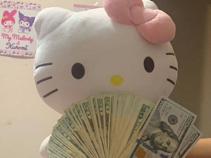 A Hello Kitty plush toy holding a fan of $100 US bills, with a 'My Melody & Kuromi' themed picture visible in the background.