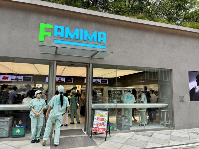 The exterior of a FAMIMA convenience store with a green and blue sign, where staff in light green uniforms stand near the entrance as customers browse inside.