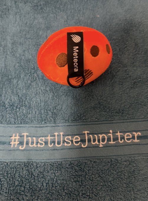 An orange circular device labeled 'Meteora' rests on a blue towel that reads '#JustUseJupiter'.