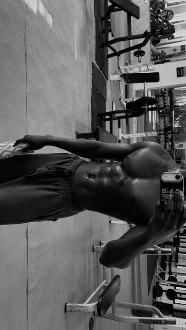A shirtless man takes a mirror selfie in a black-and-white gym photo, showcasing his physique. The image aligns with the post's motivational message about working on one's body, serving as visual proof of a fitness commitment.

No visible text appears on the phone case (it shows a partial reflection) or elsewhere in the image.