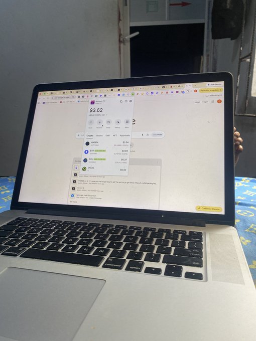 A person sits holding open a silver MacBook Pro, displaying a browser tab showing a cryptocurrency price of $3.62 for XRP, with other tokens like DIMO, ETH, SOL, and USDC visible below.