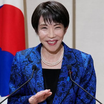 Japan's Finance Minister, Shunichi Suzuki, smiles while speaking at a press conference, representing the government's official recognition of crypto as financial assets.