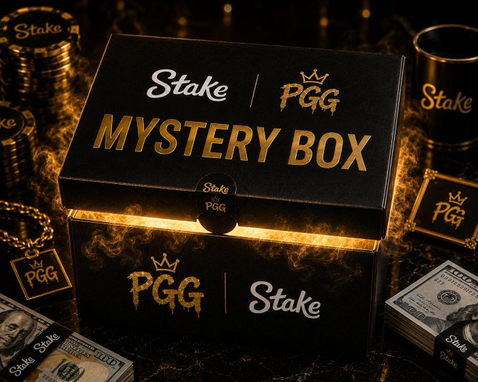 A black and gold "Mystery Box" branded with Stake and PGG logos sits surrounded by stacks of chips, cash, and gold accessories, suggesting a prize giveaway for the Stake crypto casino's PGG feature where users are prompted to reply with their username for a chance to win.