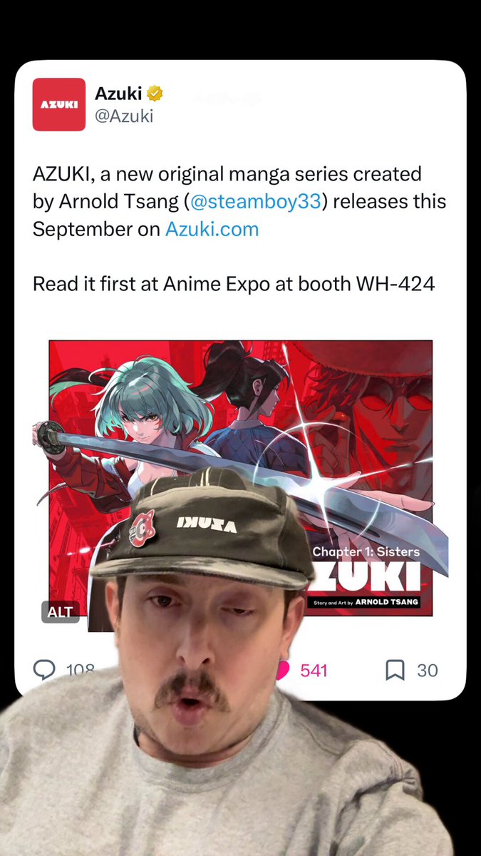 The image features a man wearing a grey shirt, with his face partially visible behind him. He has a mustache and appears to be looking directly into the camera. The background of the image shows an anime character from Azuki, which is displayed on a poster or a picture frame. The caption below the image reads "I don't think ppl fully grasp how huge this move is for @Azuki and @AzukiTCG!".