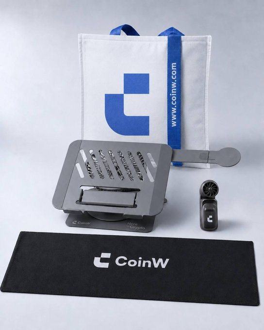 A CoinW-branded merchandise bundle is displayed, featuring a white tote bag with "www.coinw.com" and the blue CoinW logo, a black desk mat printed with "CoinW," a Hex Crypto cooling stand holding a branded device, and a small portable handheld fan that the recipient's mom found surprisingly practical. The image visually confirms the post's mention of receiving a "physical gift" from CoinW, with the portable fan being the standout item highlighted in the caption.
