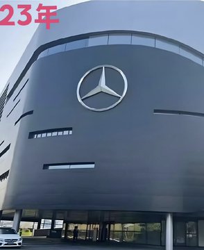 The exterior of a modern Mercedes-Benz dealership building with a large logo and red Chinese text '23年' in the upper left corner.