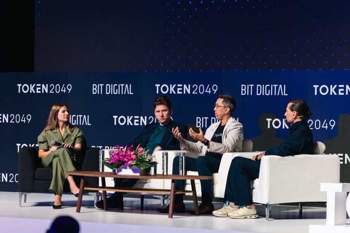 A panel discussion at the TOKEN2049 conference featuring four speakers seated on a stage with "TOKEN2049" and "BIT DIGITAL" branding visible on the backdrop behind them. The image captures the speaker engaging in discussion, illustrating the moment referenced in the post about exploring "the next generation of ETH" during their time in Tokyo, Seoul and Singapore.
