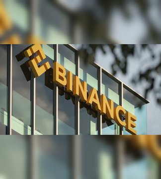 The image shows a close-up of the Binance logo and signage on a building, displayed in gold lettering. The accompanying article notes that EU regulators are scrutinizing Binance's use of MiCA's reverse solicitation exemption, as the world's largest crypto exchange attempts to continue serving European customers without securing the required license.