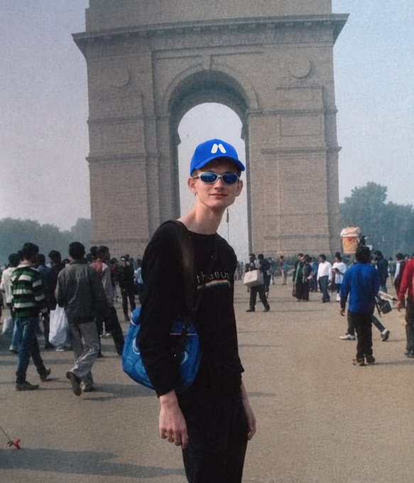 A young man wearing a blue cap with the Ethereum "Ξ" logo poses in front of the India Gate monument, connecting the iconic landmark to Ethereum's birthday celebration. The image ties the post's call to "drop a Ξ" to a real-world visual of the Ethereum symbol being worn proudly at a famous global destination.
