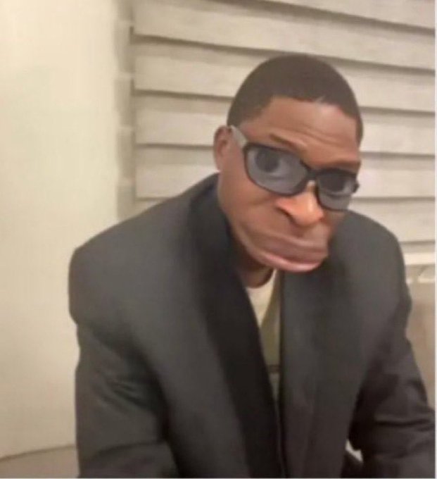 A distorted meme image of a man in a black suit and sunglasses with an exaggerated, unsettling face, looking at the camera.
