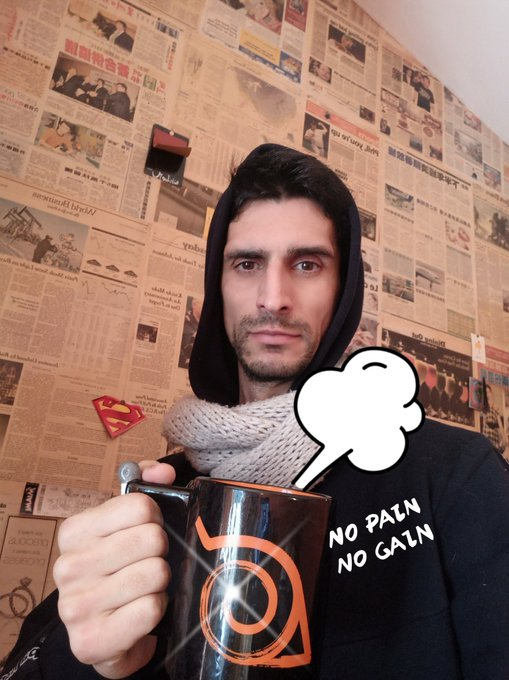 A man wearing a hoodie and a 'NO PAIN NO GAIN' shirt holds an Avenged Sevenfold coffee mug in front of a newspaper-covered wall, with a thought bubble sticker added.