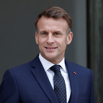 The image shows French President Emmanuel Macron in a navy suit with a dotted tie, likely featured in relation to France's proposed 31.4% tax on crypto-to-stablecoin conversions, a policy that would fall under his administration's economic agenda.