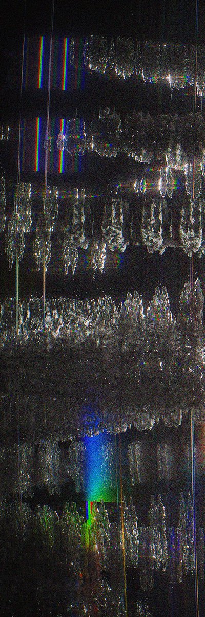 A heavily glitched, distorted image with chromatic aberration, showing fragmented patterns in dark and iridescent colors with no discernible subject.