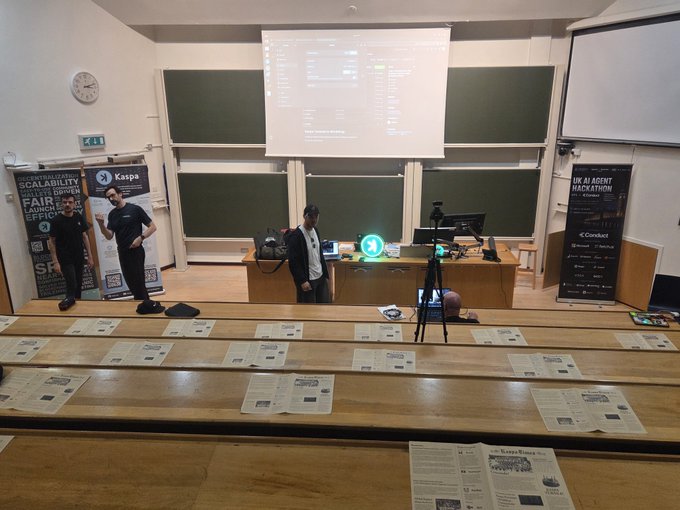 The image captures the setup of a Kaspa blockchain workshop, featuring a projector screen displaying technical content, sponsor banners from Kaspa and KastleWallet, and tiered classroom seating with informational papers laid out on the desks in preparation for attendees. This setting connects to the post about the Side Quest dinner event where participants can earn discounts by paying with $KAS, as the workshop serves as the gathering point for the Kaspa community before they head to WolfysBar.