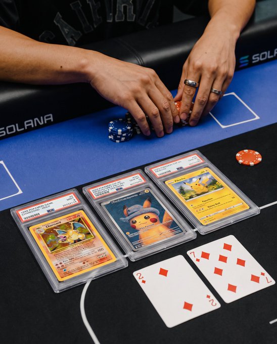 A person's hands handling blue and orange poker chips at a casino table branded with the 'Solana' logo, with Pokémon trading cards (Charcadet, Raichu, and a Poké Ball card) and two playing cards (2 of Diamonds, 7 of Diamonds) displayed on the felt.
