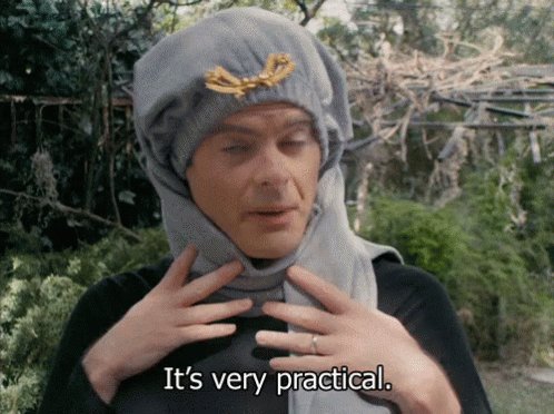 The image features an actor wearing a grey hat with a gold brooch and holding his hands up, as if he's explaining something or posing for a photo. The caption below the image reads "It's very practical." This suggests that the actor is discussing the effectiveness of Quip network security measures in terms of practicality rather than focusing on the visual elements of the scene.