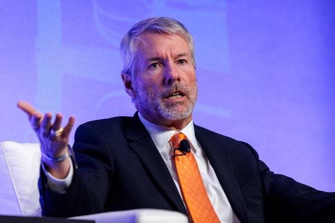 Michael Saylor, executive chairman of MicroStrategy and prominent Bitcoin advocate, speaks at a conference with an orange tie, gesturing as he discusses the merits of owning Bitcoin as a counterparty-free asset that grants direct exposure to the global digital economy.