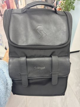 A black leather backpack with the Bitget logo embossed on the front pocket, displayed indoors.