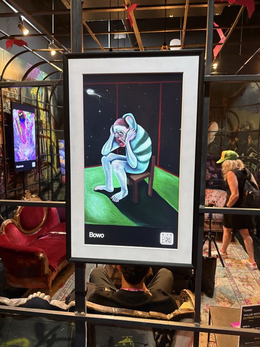 A framed artwork titled "BOWO" depicts a melancholy figure in a red cap sitting hunched on a chair against a starry, green-tinged background, displayed at the Futurist Conference 2026. The piece, captioned "Hollowed," evokes themes of isolation that align with the post's atmospheric tone.