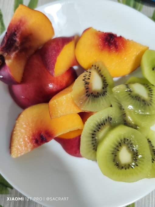 A white plate filled with sliced peaches and kiwi fruit, with the watermark 'XIAOMI 12T PRO | @SACRA97' in the bottom left corner.