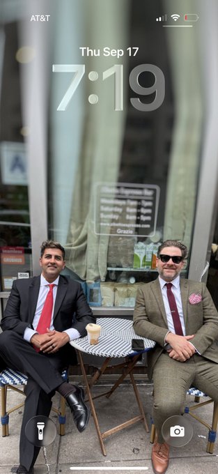 An iPhone lock screen showing Thursday September 17 at 7:19 with AT&T carrier, featuring a photo of two men in suits sitting at a Parisian café table.
