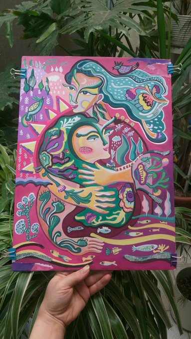 The image features a hand holding up an art piece that appears to be a painting or a collage. The artwork depicts two people embracing each other with flowers surrounding them. The colors used are predominantly pink, green, and blue, creating a vibrant and lively atmosphere. The background of the artwork is filled with various elements such as fish, plants, and birds, adding depth and complexity to the scene. The image also includes text that reads "Scent of the Inner Garden" and "Not for judging, not for correcting, not to resemble any other image others might prefer; only to see— exactly as I am."