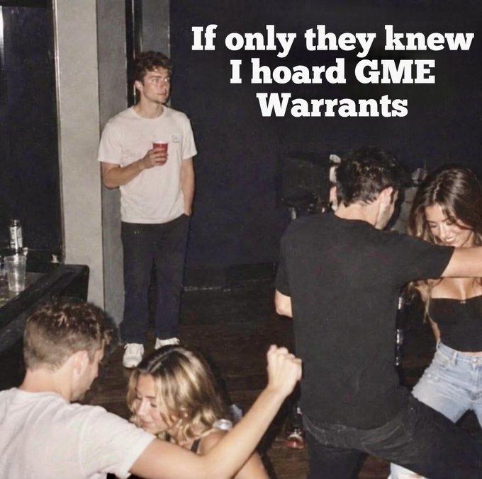 A young man stands alone holding a red solo cup at what appears to be a party, while others dance nearby, with overlaid text reading "If only they knew I hoard GME Warrants." The meme humorously captures the "secret investor hiding in plain sight" vibe from the post, portraying the user as someone concealing their strategic GME warrant position while others are distracted by superficial things — perfectly matching the confident, "strapped tf up and we ride" energy of betting on GME warrants for upside as the underlying decays.