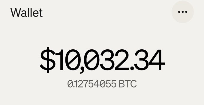 The image displays a digital wallet interface showing a balance of $10,032.34, which corresponds to 0.12754055 BTC. This screenshot visually confirms the poster's achievement of reaching their $10,000 Bitcoin savings goal, marking the milestone that prompted them to shift focus toward Roth IRA contributions while maintaining smaller DCA (dollar-cost averaging) purchases of BTC.