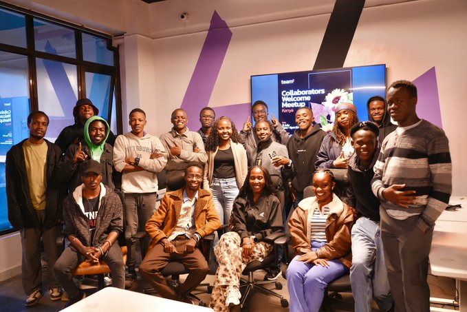A group photo of approximately 17 people posing together in an office space, with a screen in the background displaying "Collaborators Welcome Meetup" and a Tequila brand logo visible.