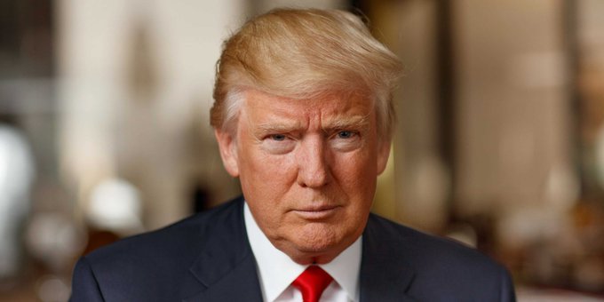 The image is a close-up of President Trump wearing a suit, tie with red collar, and standing against a blurred background, likely a room or building with chairs and tables. The caption below reads: "President Trump' s memecoin is now down 97.6% from its peak. $10,000 invested last year in  TRUMP is worth just $236 today." This quote provides context about the historical significance of President Trump's investment in the company and suggests that it has lost 90% of its value over the past decade.