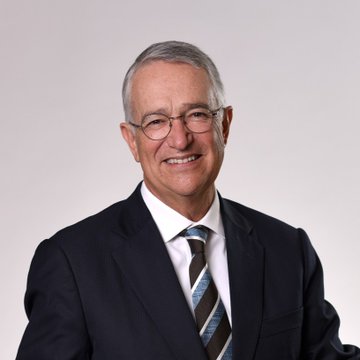 A professional headshot of an older man with gray hair and glasses, wearing a dark suit and blue striped tie, smiling warmly against a light gray background. The image likely depicts Ricardo Salinas Pliego, the Mexican billionaire referenced in the post who advocates for Bitcoin as a hedge against fiat currency inflation.
