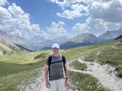 A smiling man in a white cap and dark shirt stands on a scenic mountain trail with lush green valleys and snow-capped peaks behind him. The post highlights the "everywhere for everybody" reach of $UFD (Unicorn Fart Dust), humorously suggesting the token's universal presence—even in remote alpine landscapes.