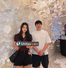 Two people pose for a photo in front of a reflective wall, overlaid with the 'Unitas Labs' logo.